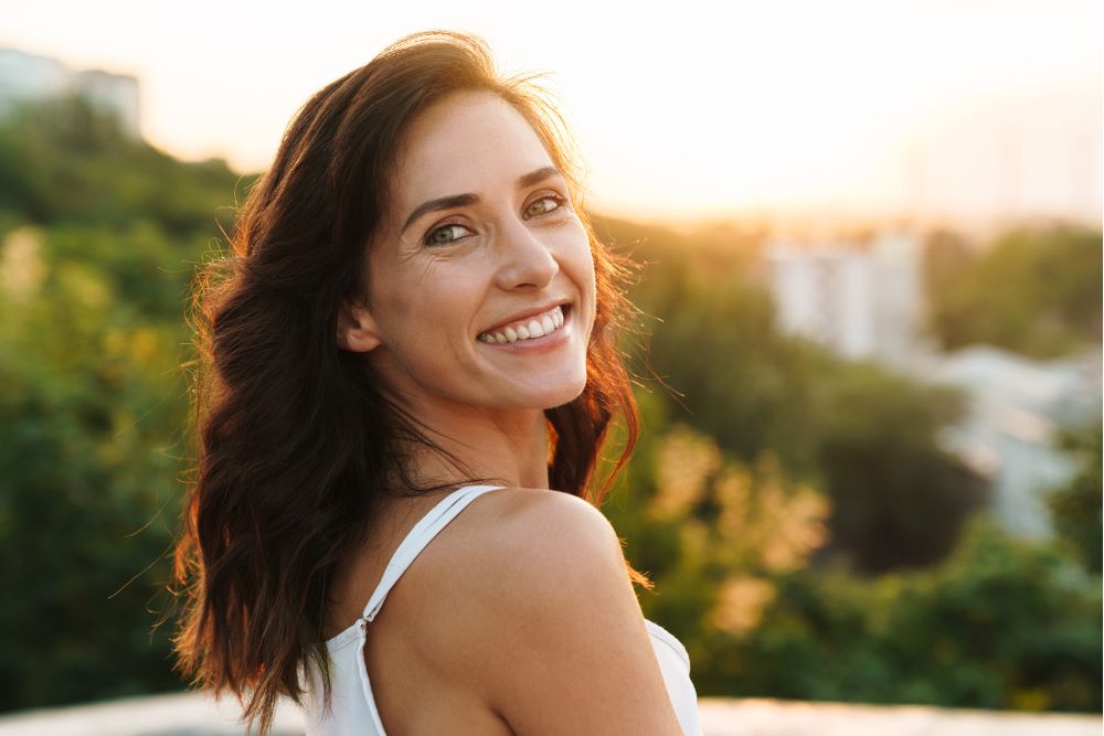 Smiling woman outdoors with bright, healthy teeth, representing confidence after cosmetic dental care