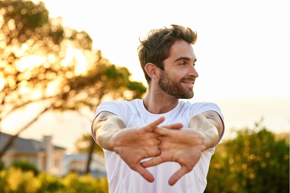 Man stretching outdoors with a relaxed smile, representing comfort and well-being after dental care
