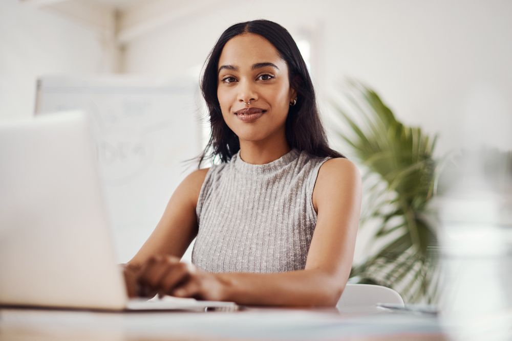 Woman working on laptop with a subtle smile, representing confidence and comfort after dental care