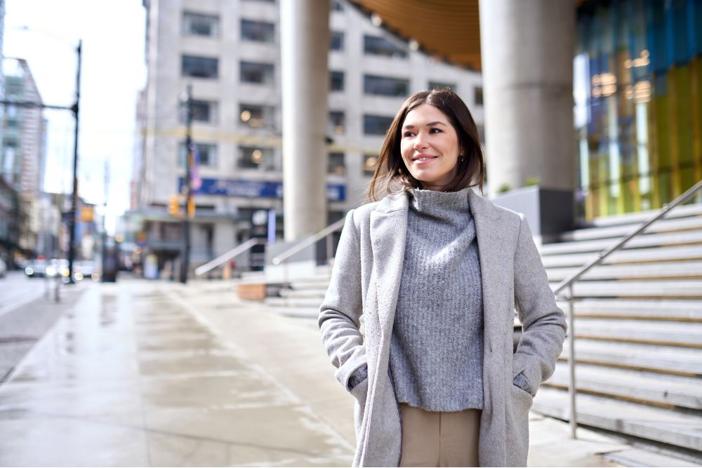 Woman walking in a city with a confident smile, representing healthy teeth and confidence after dental care