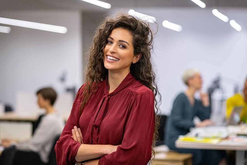 Smiling woman with bright, healthy teeth in a professional setting, representing confidence after dental care