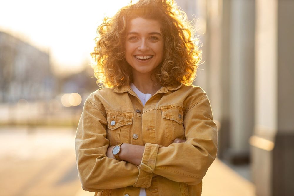 Smiling woman outdoors with bright, healthy teeth, representing confidence after cosmetic dental care