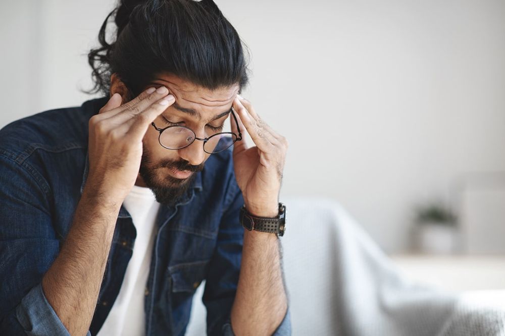 Man holding temples in discomfort, representing headaches or TMJ-related jaw pain