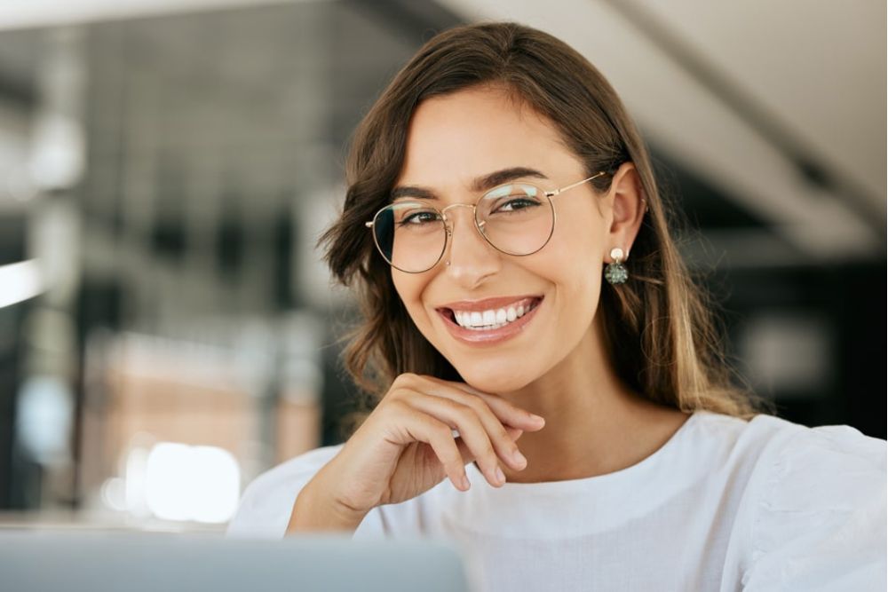 Smiling woman with glasses showing bright, healthy teeth, representing confident results from cosmetic dental care