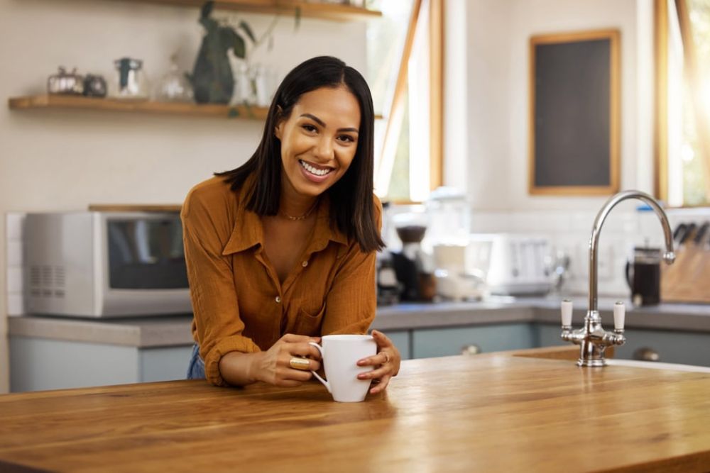 Smiling woman enjoying a drink comfortably, representing relief from tooth sensitivity after dental care