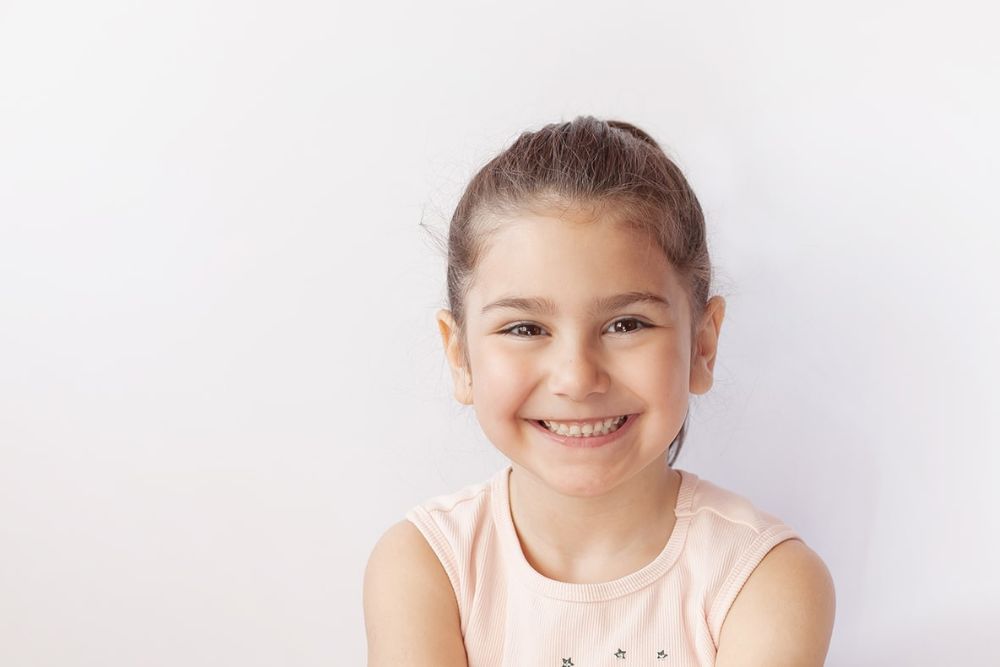Smiling young girl with healthy teeth, representing positive pediatric dental care experience