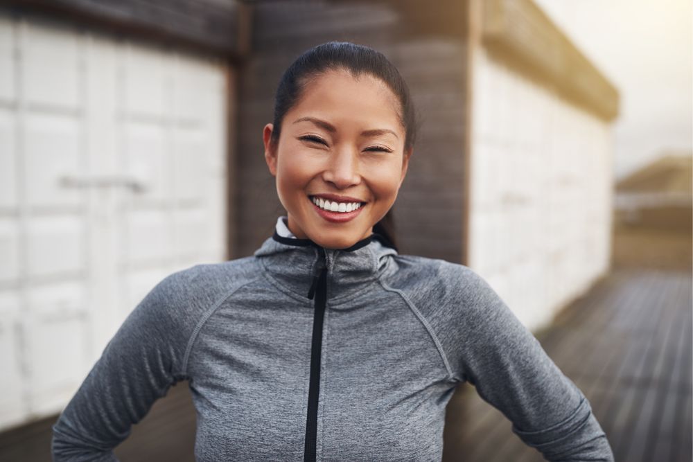 Smiling woman in athletic wear with bright, healthy teeth, representing confidence and wellness after dental care