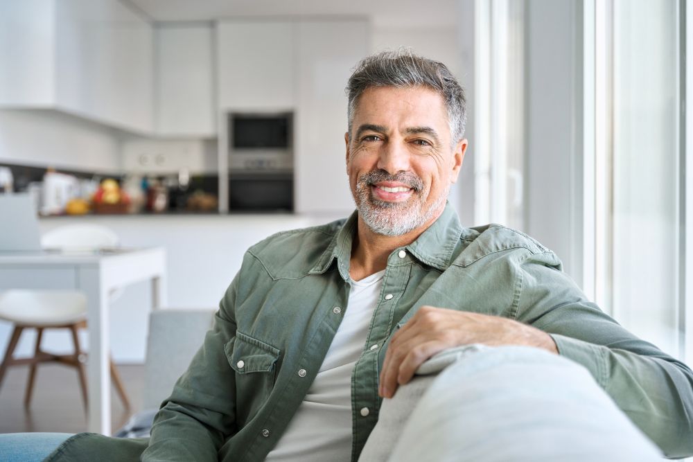 Smiling older man with healthy teeth at home, representing confident results from restorative or cosmetic dental care