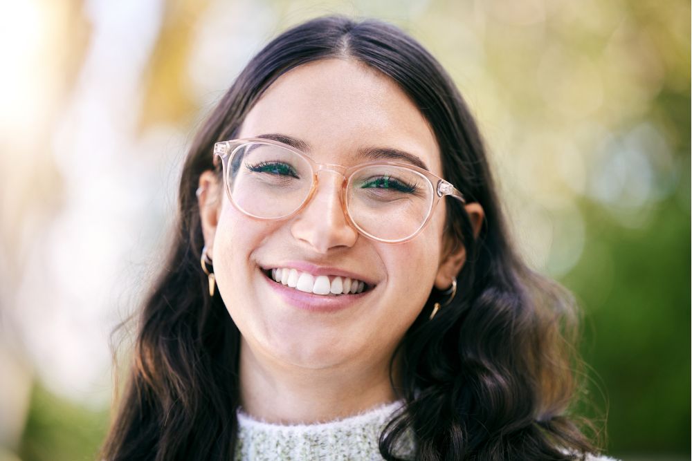 Smiling woman with glasses and bright, healthy teeth, representing confidence after cosmetic dental care