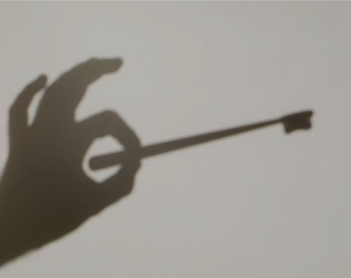 Shadow of a hand holding a key, symbolizing access, security, or unlocking solutions